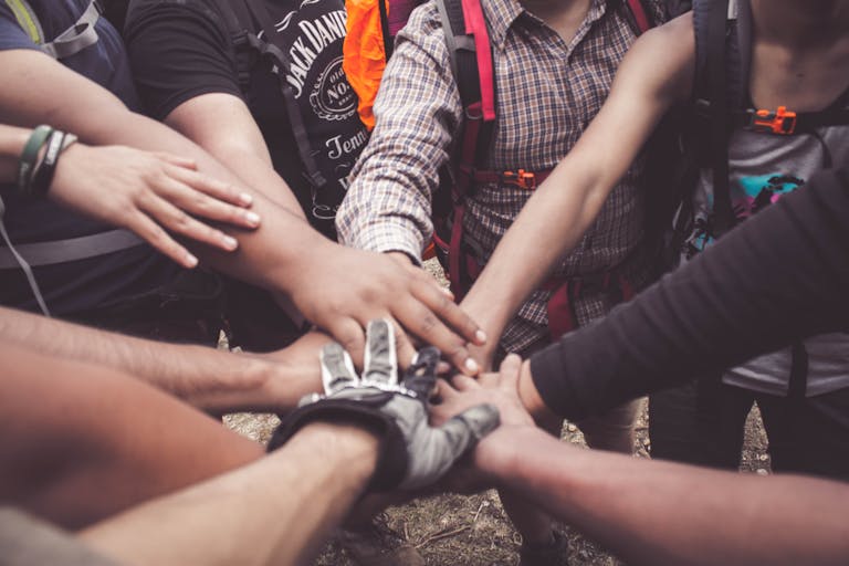 A group of diverse individuals join hands for community support